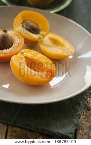 Whole orange apricots with red blush, from above, space for text. Open apricot with stone and leaves. On rustic white wood.