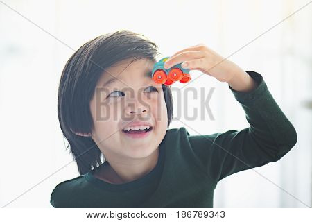 Cute asian child playing toy cars in the room