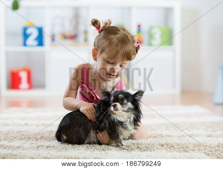 Lovely little girl and her pet dog in children room