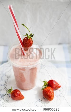 Strawberry-banana smoothie with milk or yoghurt. Healthy summer smoothies to go in a plastic cup
