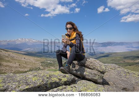 Woman Using Mobile On Top Of Mountain