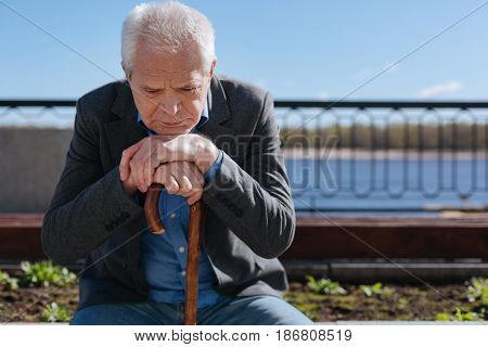 Do not back to past. Clever, thoughtful white-haired pensioner remembering his wife and mulling over his future while sitting on the bench