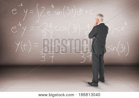 Thoughtful businessman standing back to camera against empty room