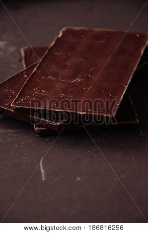 Whole And Pieces Of Dark Chocolate Bars On A Darkbackground  At Monochrome Setting. Toned.