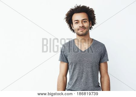 Portrait of stong and handsome african man looking at camera posing over white wall. Confident entrepreneur and student. Copy space.