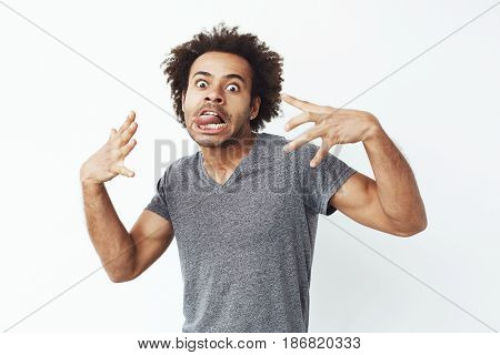 Young cheerful african man making funny face fooling over white background.