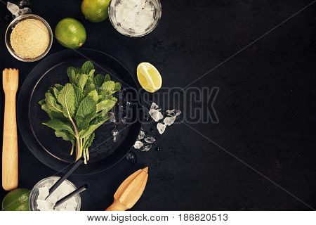 Mojito cocktail ingredients (fresh mint, lime, ice) on rustick background