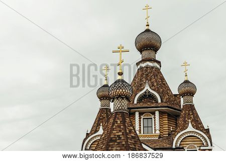 Domes and crosses of a wooden orthodox church against a cloudy sky background