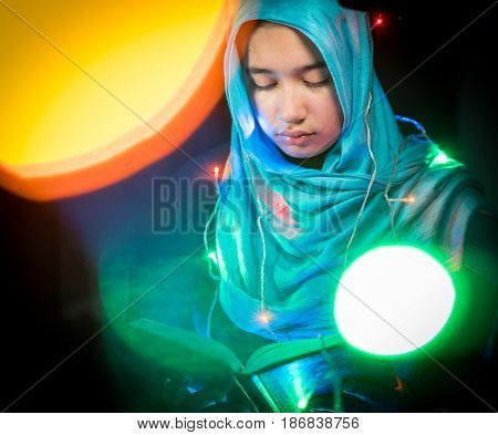 Muslim woman praying in dark room with nice lights around her