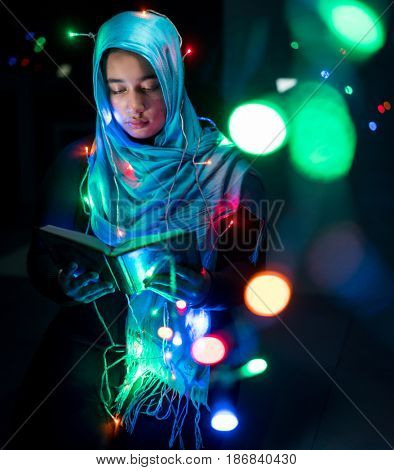 Muslim woman praying in dark room with nice lights around her