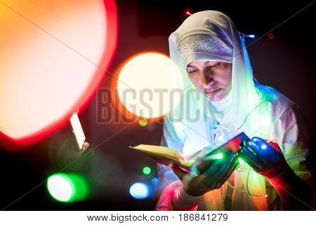 Muslim woman praying in dark room with nice lights around her