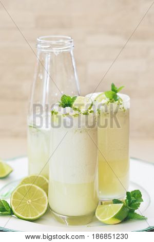 Brazilian lemonade or limeade in retro bottle and glasses,  decorated with lime slices and mint . Macro, selective focus, blank space