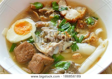 boiled Chinese pasta with pork and entrails topping creamy egg yolk in soup