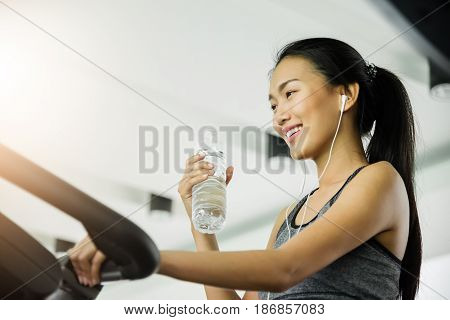 Asian woman in sportswear drinking water after workout at the gym.