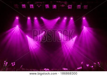 Purple light from the spotlights through the smoke in the theatre during the performance. Lighting equipment.