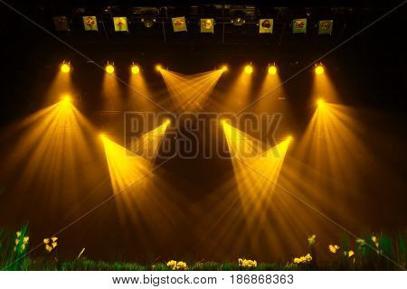 The yellow light from the spotlights through the smoke at the theater during the performance. Lighting equipment.
