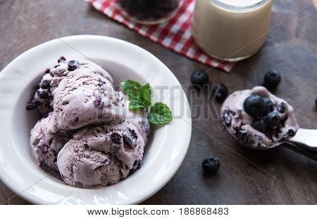 Blueberry homemade ice cream with mint leaves and Spoon for ice cream on stone slate background. Ingredients for ice cream