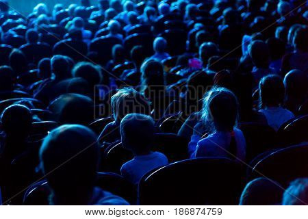 People, children, adults, parents in the theater watching the performance.