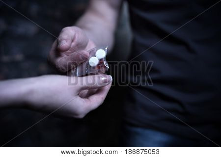 Soiled illegal business . Daring crafty mature man selling packet with drugs while sharing and offering heroin dose