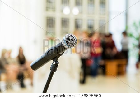 Wireless microphone on the stand at a reception in the hall. People in the background. Blurred background. Bokeh.