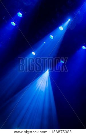 The blue light from the spotlights through the smoke in the theatre during the performance. Lighting equipment.
