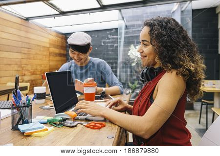 Startup of two multiethnic people discussing joyfully ideas in a modern coworking espace