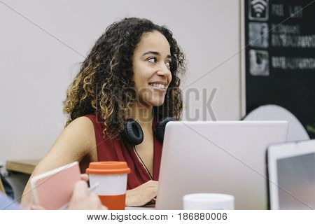 Young african american woman with headphones talking with her colleagues working in a modern coworking espace
