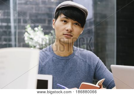 Young chinese entrepreneur listening to his colleagues working in a coworking espace