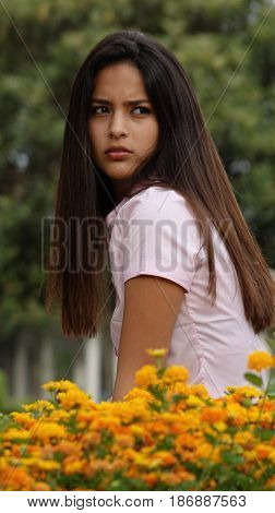 A Serious Teen Girl Sitting Among Flowers