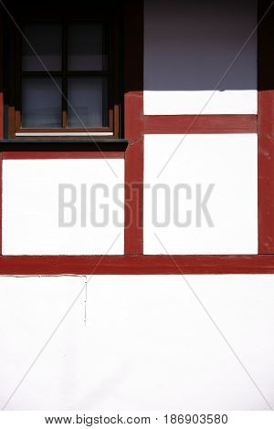 The close-up of the beam construction of a half-timbered house with window in strong sunlight.