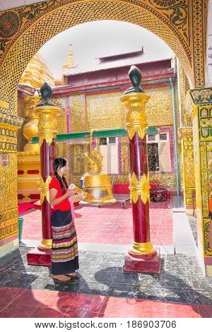 MANDALAY,MYANMAR - MARC 7, 2017: Myanmar woman ringing the bell  Su Taung Pyi Pagoda on top of Mandalay Hill on March 7, 2017, in Mandalay, Myanmar (Burma)
