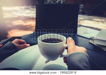 Hands on a woman drinking coffee working in a natural garden on a vacation.