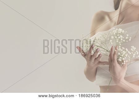 Lovely girl in white lingerie. Sensual photo. She holds white spring flowers near her breast. Man is unrecognizable