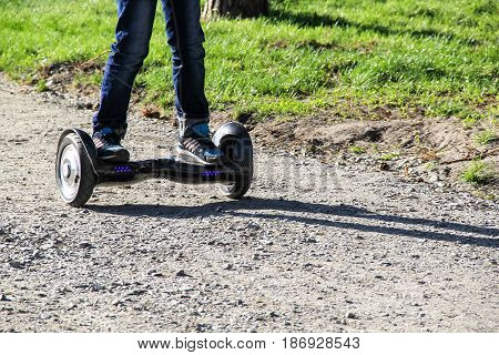 Legs of boy riding on self-balancing mini hoverboard in the city street. Electronic scooter outdoors - personal portable eco transport gyro scooter hyroscooter smart balance wheel mini segway