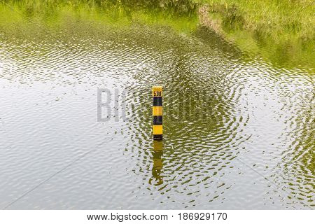 Water level indicator pole in natural lake showing the depth of water.
