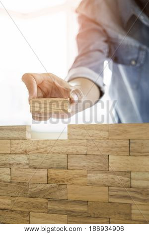Hand Of Engineer Playing A Blocks Wood Tower Game (jenga) On Blueprint Or Architectural Project Conc