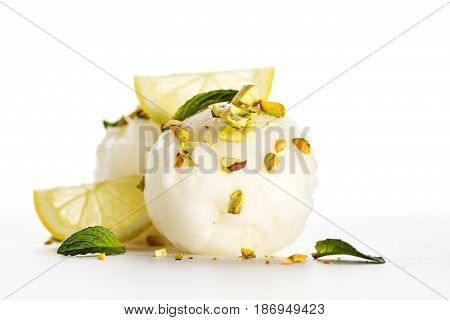 Tasty appetizing decorated lemon ice sorbet scoops with lemon pistachio waffles and mint on white plate. Beautiful Food Styling. Closeup