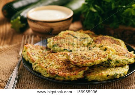 Vegetarian food - zucchini fritters on wooden background.