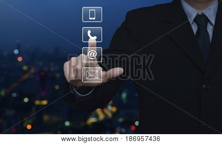 Businessman pressing telephone mobile phone at and email buttons over blur colorful night light city tower Customer support concept