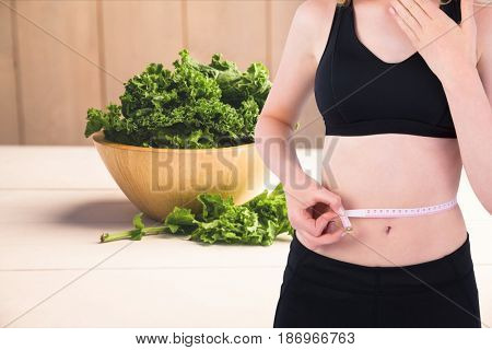 Digital composite of Midsection of woman measuring waist with kale in background