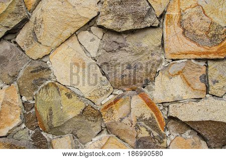 The wall is lined with beige cobblestones of various sizes fastened with concrete.