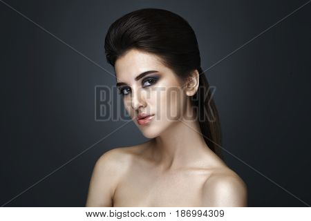 Beautiful woman with evening make-up and updo. Fashion photo. Girl ower dark background. Studio shoot.