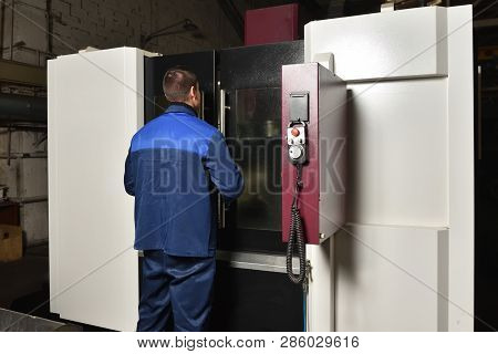 The Worker In Blue Workwear, The Operator Of The Cnc Machine, Oversees The Process And Controls It. 