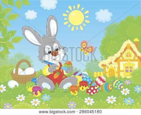 Little Grey Bunny Painting Easter Eggs On Green Grass Among Flowers On Its Front Lawn Near A Small H