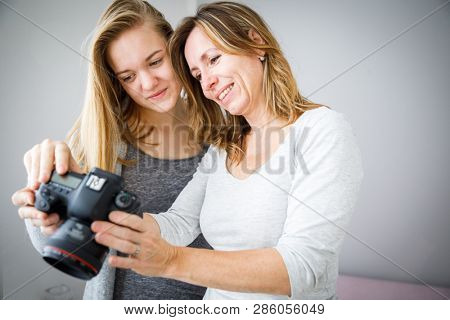 Mother and daughter taking photos and checking them on a modern digital DSLR camera