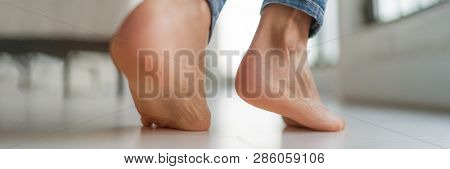 Barefoot feet walking on heated floors at home - Comfort lifestyle healthy foot care for cracked skin heels woman legs banner panorama.