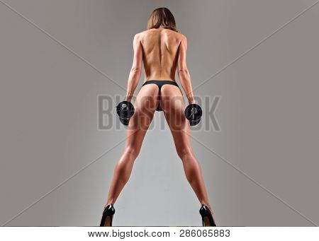 Female Fitness Model. Middle Eastern Female Doing Biceps Curl With Dumbbells In The Gym