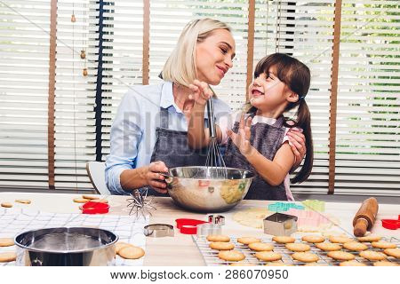 Mother And Daugthter Having Fun Cooking Togather And Learning To Make A Cake While Baking In Kitchen