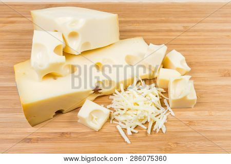 Partly Sliced And Grated Swiss-type Cheese On Cutting Board
