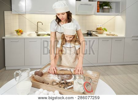 Cheerful Mother Teaching Daughter And Helping Squeezing Dough. Woman And Girl Cooking Chocolate Cook